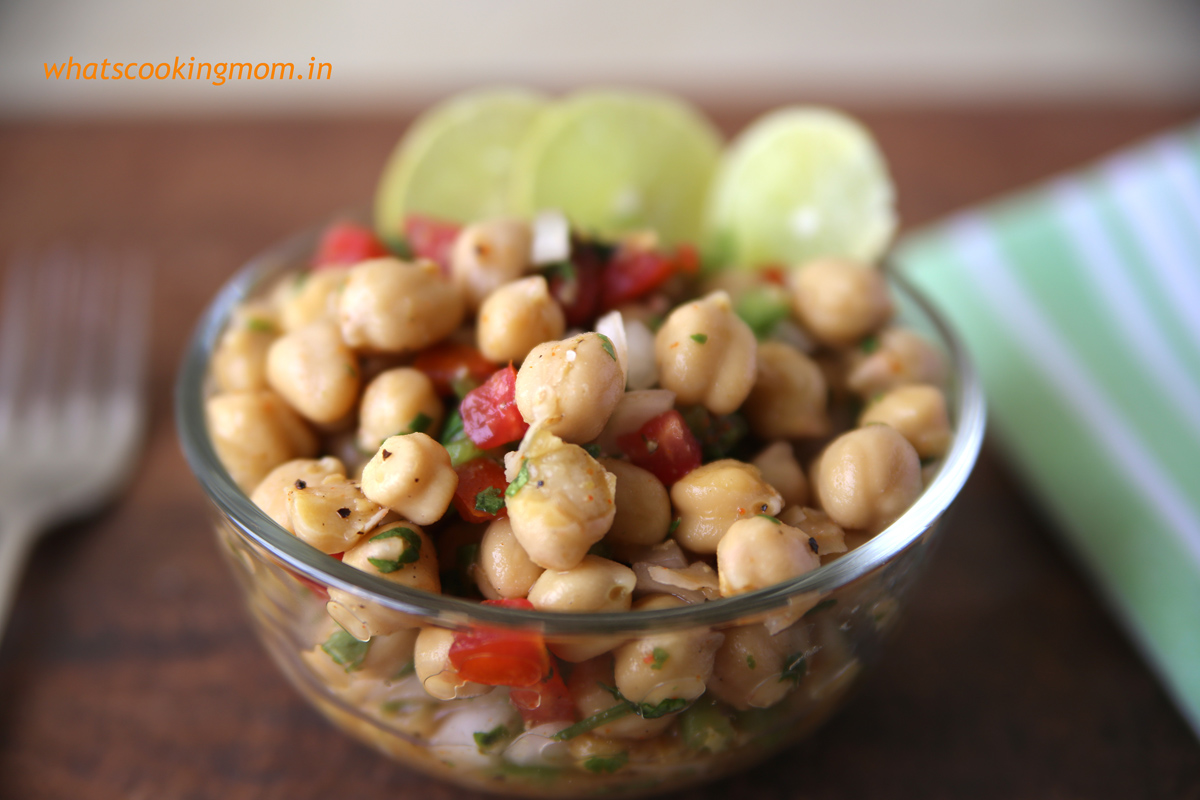 Chana chaat served in a glass bowl on a wooden table