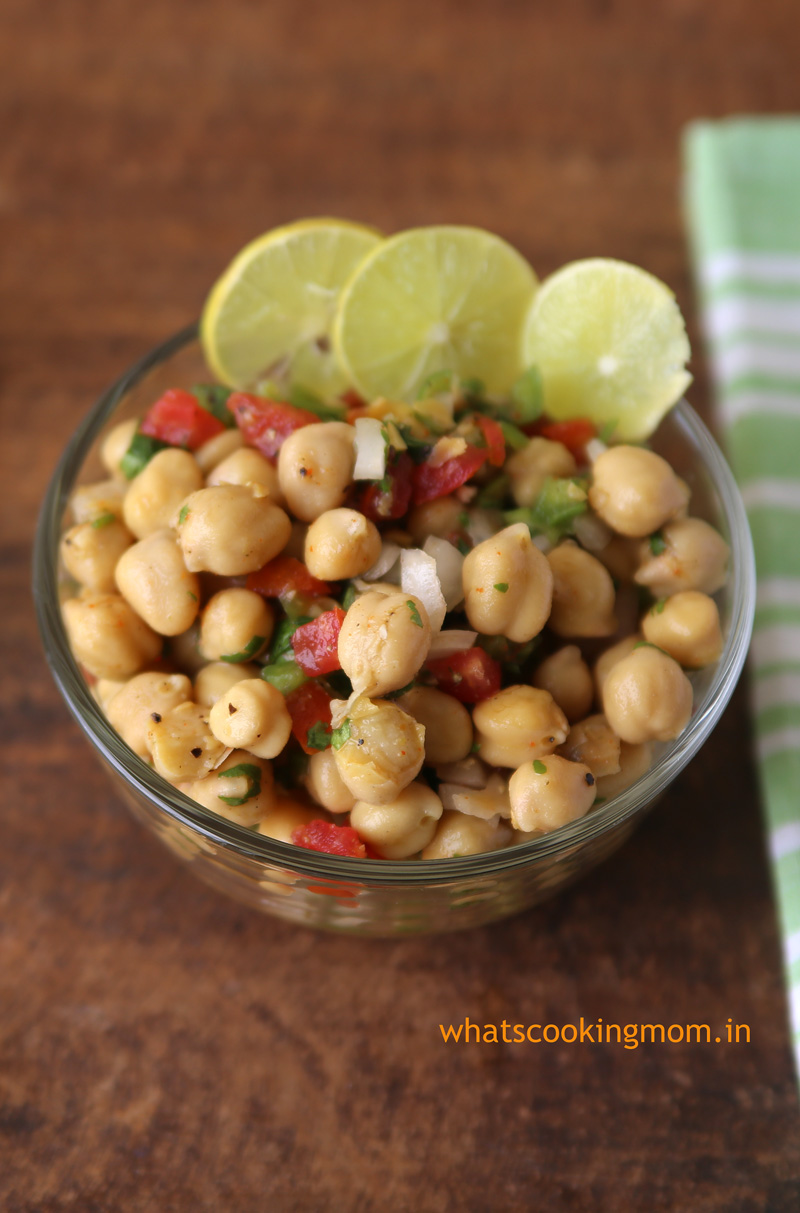 Chickpea salad served in a glass bowl garnished with lemon wedges