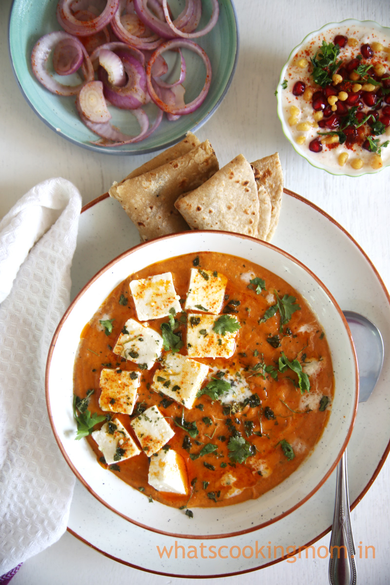 Paneer Butter masala served in a bowl with roti, onion salad and raita